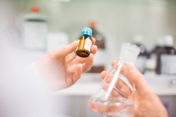 holding medicine bottle and flask. Close-up of experts working in